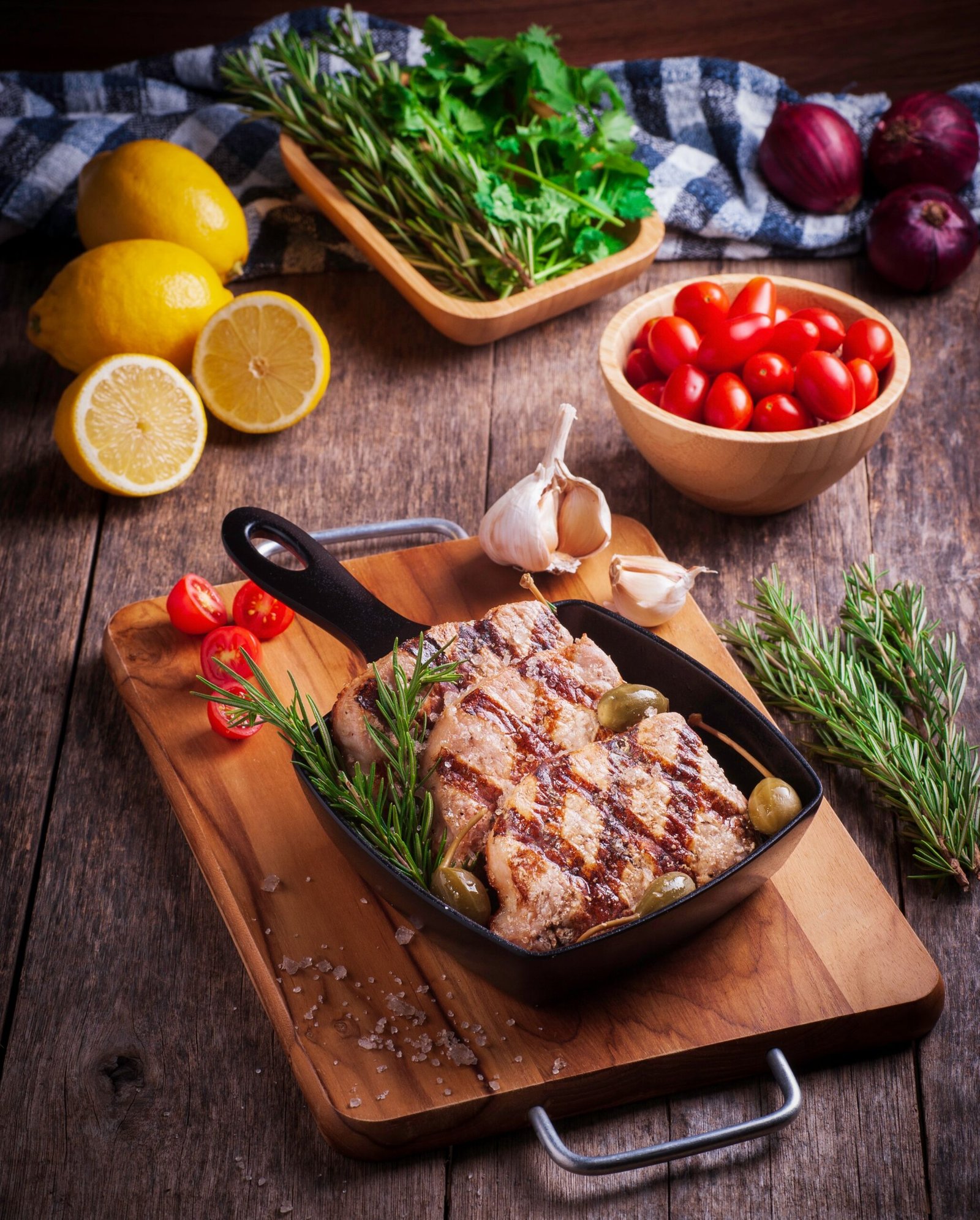 Seared chicken in a skillet with cherry tomatoes, olives, and herbs