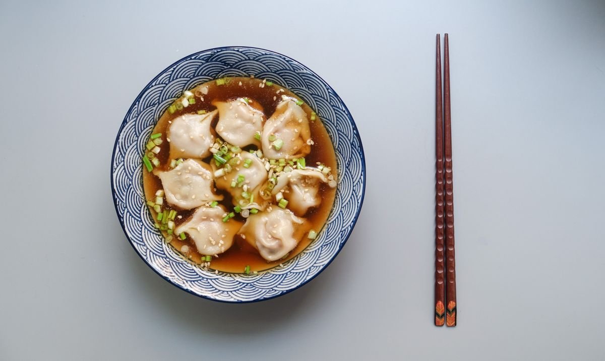 Bowl of dumplings in broth with chopsticks
