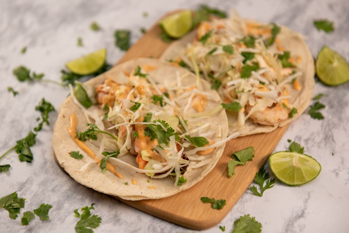 Shrimp tacos with cabbage slaw, cilantro and lime wedges